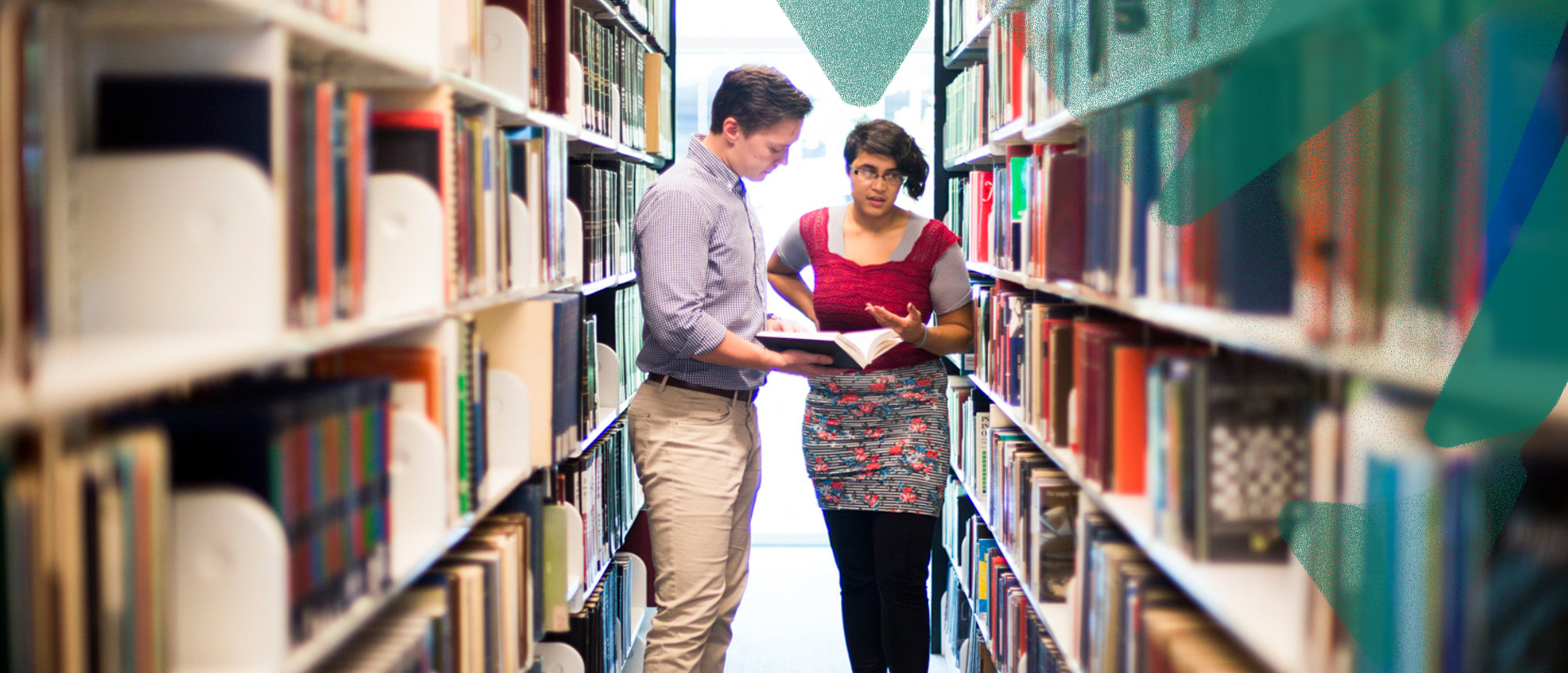student and faculty whisper in an Emory library