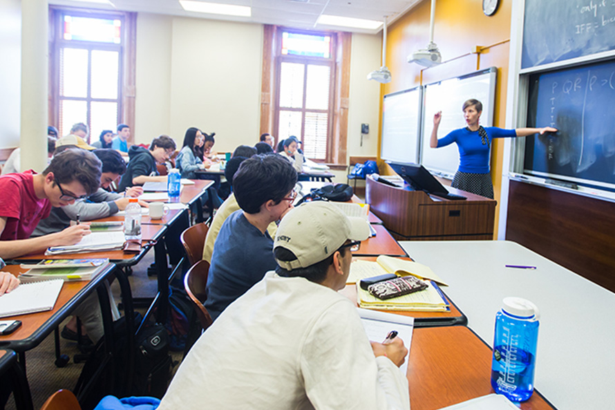 students lsten to a professor at the blackboard