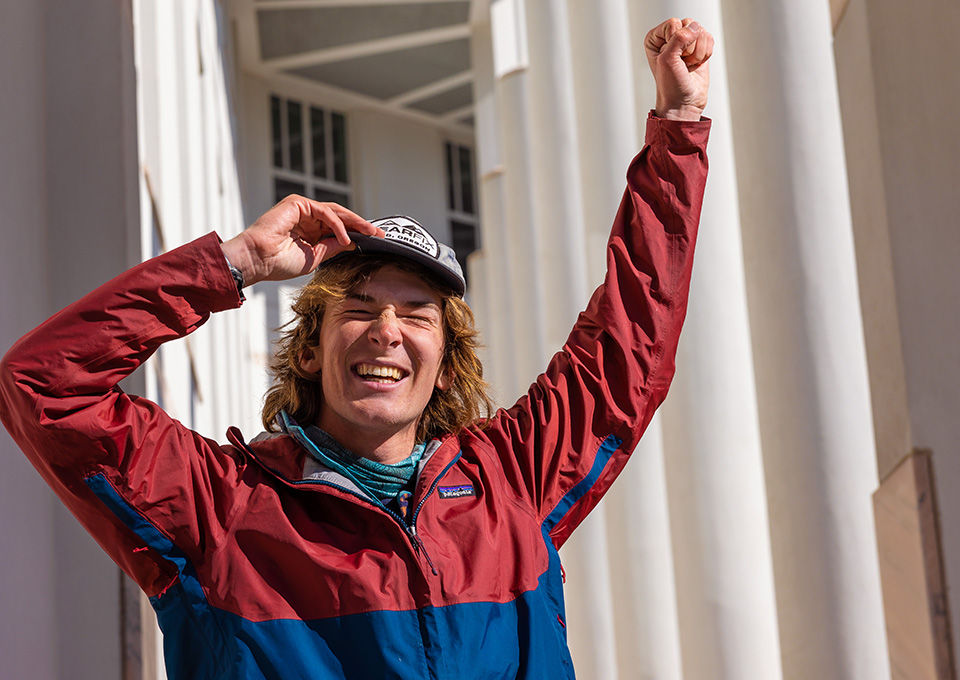 Emory student squinting in the sun with arm raised